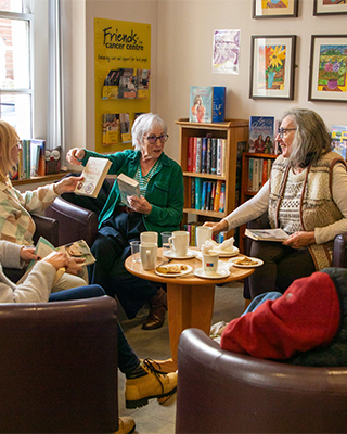 Libraries NI Making A Difference - photo of people sitting in a reading corner at the Macmillan Cancer Information and Support Centre in Belfast; they are holding books and chatting
