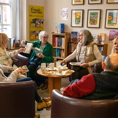 Libraries NI Making A Difference - photo of people sitting in a reading corner at the Macmillan Cancer Information and Support Centre in Belfast; they are holding books and chatting